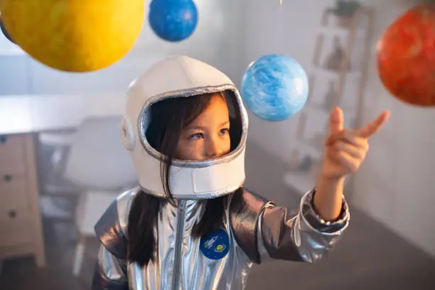 : Woman in NASA spacesuit on Mars-like terrain, holding helmet, gazing at starry sky.